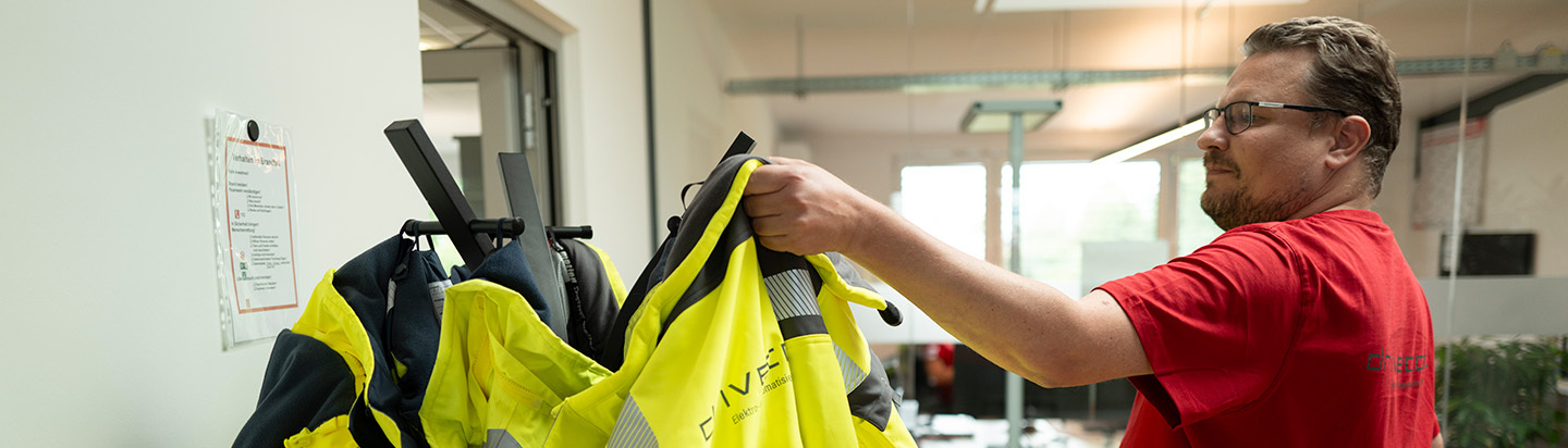 Ein Mitarbeiter nimmt eine Jacke von der Garderobe